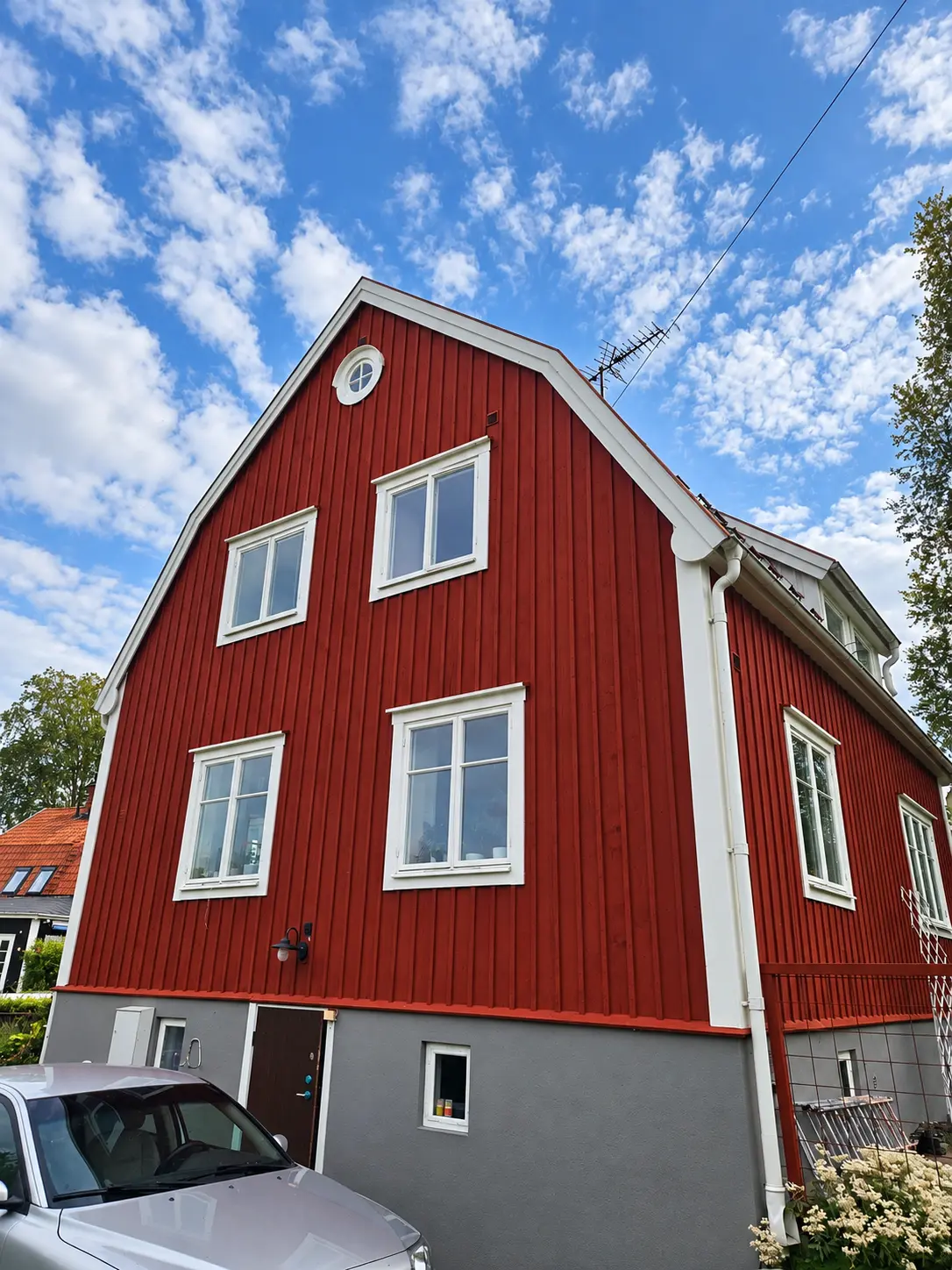 Rödmålad fasad med fönster, dörr och vita lister.