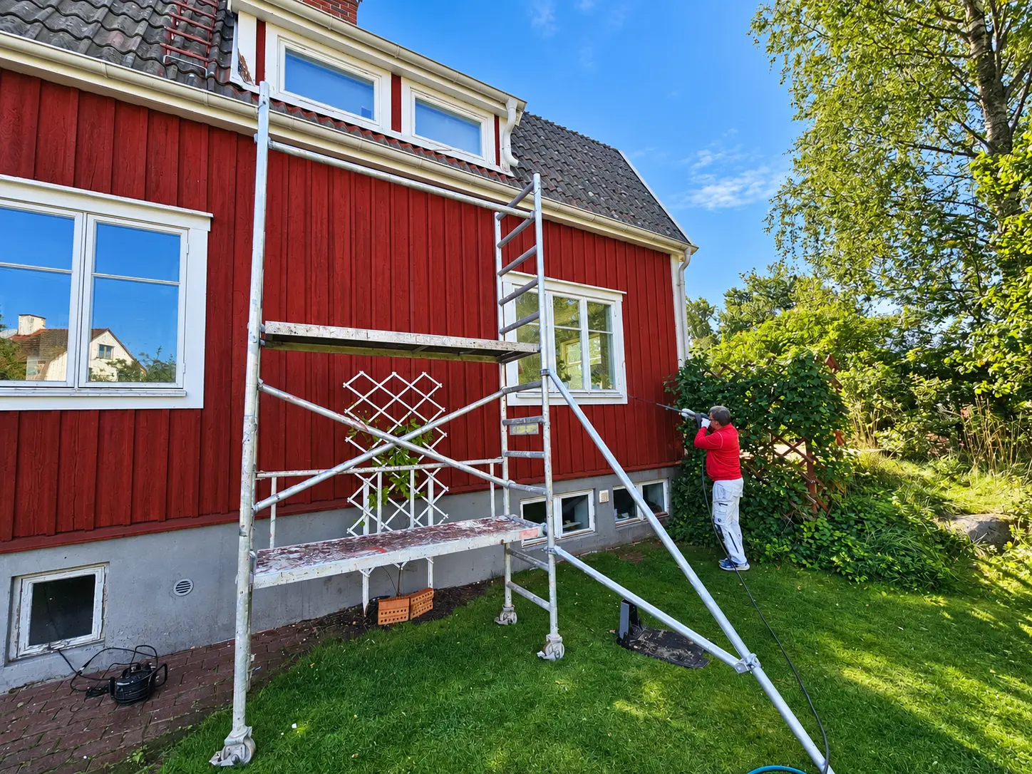 Fasad som tvättas inför målning, med byggställning vid huset.