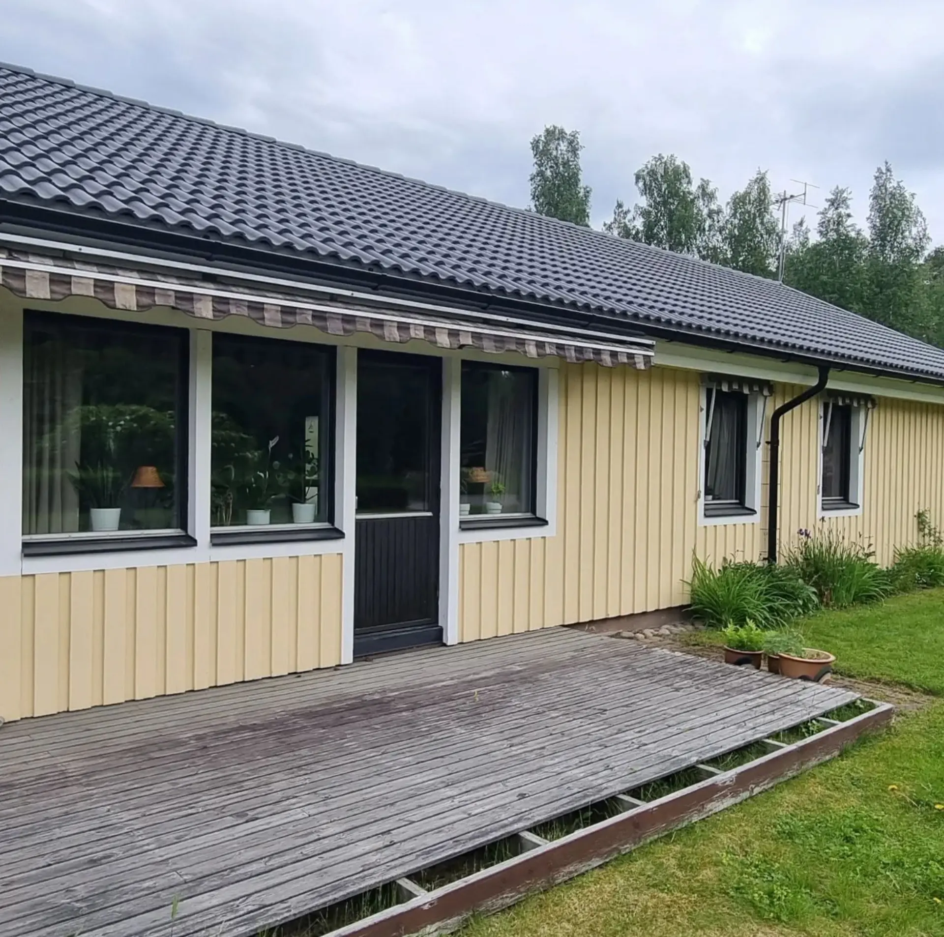 Ljusgul fasad med veranda före ommålning.